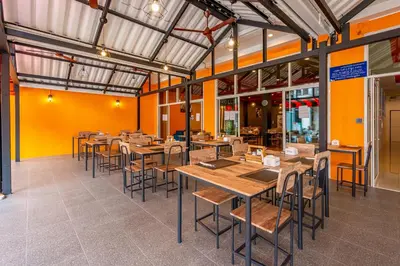an empty restaurant with wooden tables and chairs at Nice to meat you Rooms in Patong Beach