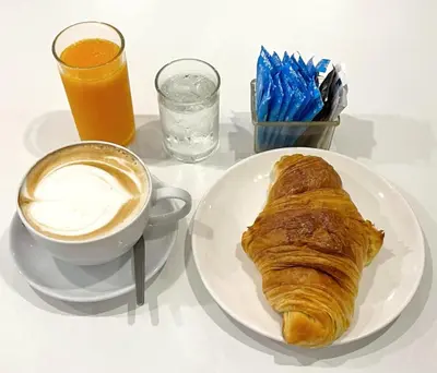 a white plate with a pastry and a cup of coffee at Nice to meat you Rooms in Patong Beach