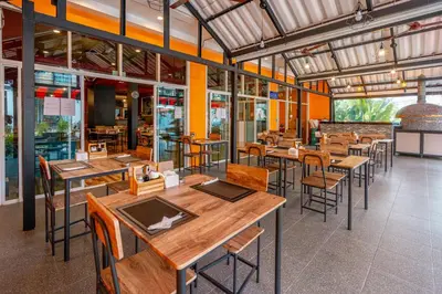 an empty restaurant with wooden tables and chairs at Nice to meat you Rooms in Patong Beach