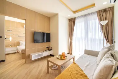 a living room with a couch and a tv at Calypso Garden Residences by Beringela in Phuket Town