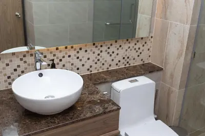 a bathroom with a sink and a toilet and a mirror at Calypso Garden Residences by Beringela in Phuket Town