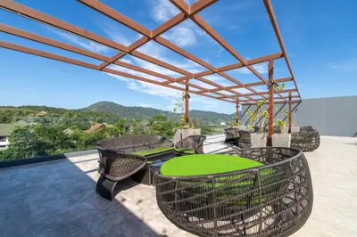 a patio with chairs and tables on a roof at Calypso Garden Residences by Beringela in Phuket Town
