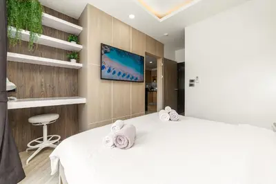 a bedroom with a white bed and a tv at Calypso Garden Residences by Beringela in Phuket Town