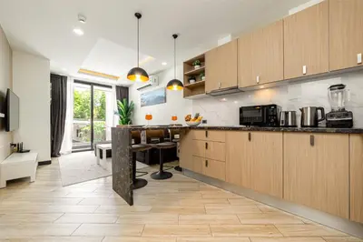 a kitchen with wooden cabinets and a dining table at Calypso Garden Residences by Beringela in Phuket Town