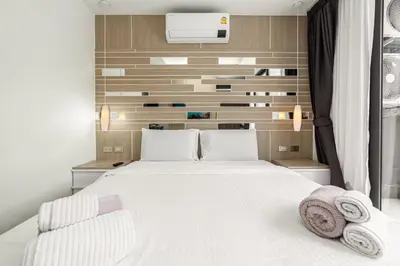 a bedroom with a white bed and a wall at Calypso Garden Residences by Beringela in Phuket Town
