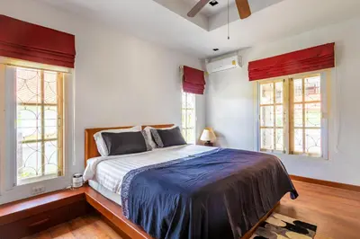 a bedroom with a bed and two windows at Recommend a warm Thai style private swimming pool villa with convenient traffic and living, walking 700 meters to the the beach in Kamala Beach