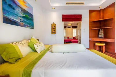 a bedroom with a large white bed with colorful pillows at Recommend a warm Thai style private swimming pool villa with convenient traffic and living, walking 700 meters to the the beach in Kamala Beach