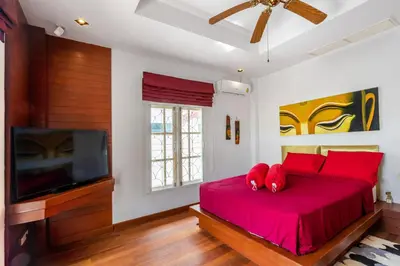 a bedroom with a bed with red pillows and a tv at Recommend a warm Thai style private swimming pool villa with convenient traffic and living, walking 700 meters to the the beach in Kamala Beach