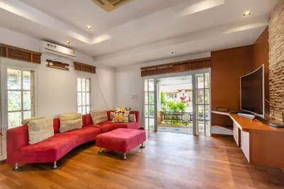 a living room with a red couch and a flat screen tv at Recommend a warm Thai style private swimming pool villa with convenient traffic and living, walking 700 meters to the the beach in Kamala Beach