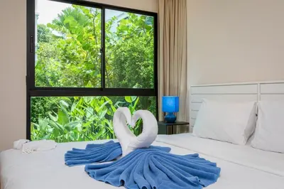 a bed with two white swans in a blue blanket at The Title Condo by Tropiclook in Rawai Beach