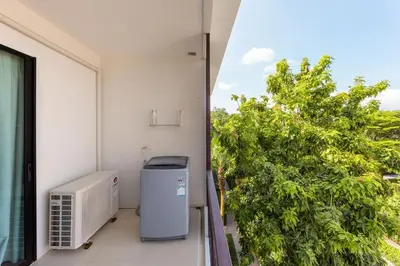 an apartment balcony with a heater and a tree at The Title Condo by Tropiclook in Rawai Beach