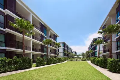 an apartment complex with palm trees and a lawn at The Title Condo by Tropiclook in Rawai Beach