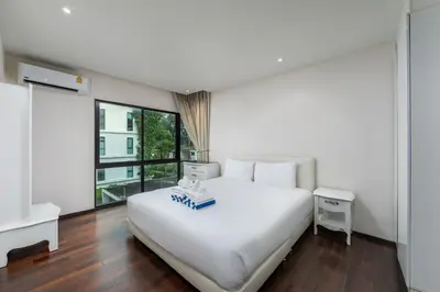 a white bedroom with a white bed and a window at The Title Condo by Tropiclook in Rawai Beach