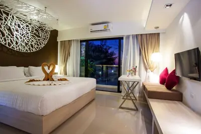 a bedroom with a bed and a large window at Coral Inn in Karon Beach