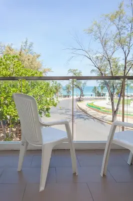 a white chair on a balcony with a view of the ocean at Coral Inn in Karon Beach