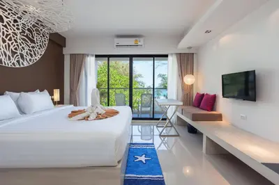 a hotel room with a large bed and a desk at Coral Inn in Karon Beach