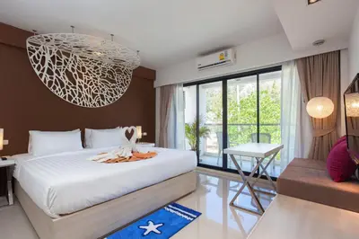 a bedroom with a bed and a chandelier at Coral Inn in Karon Beach