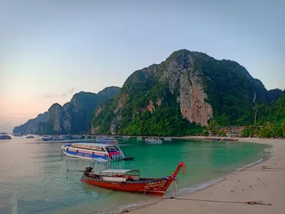 two boats on a beach with a mountain in the background at Harmony House-SHA Plus in Phi Phi Don