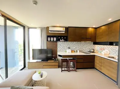 a living room with a couch and a kitchen at Citygate in Kamala beach - Perfect Stay for Digital Work in Kamala Beach