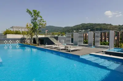 a large blue swimming pool with benches and a building at Aristo 2 Phuket, Surin beach in Surin Beach