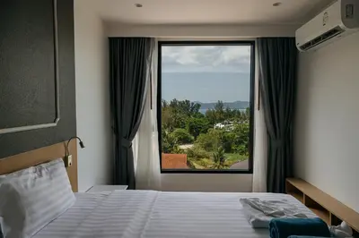 a bedroom with a bed and a large window at Aristo 2 Phuket, Surin beach in Surin Beach