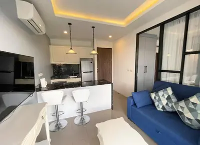 a living room with a blue couch and a kitchen at Modern Condo Palmyrah by Lofty in Surin Beach