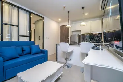 a living room with a blue couch and a kitchen at Modern Condo Palmyrah by Lofty in Surin Beach