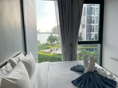 a woman laying on a bed in front of a window at Best location in Laguna-modern apartment at Cassia in Bang Tao Beach