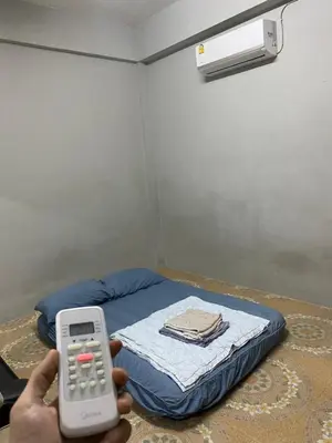 a person holding a remote control in front of a bed at Кондо в райском уголке Равай in Rawai Beach