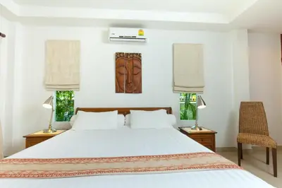 a bedroom with a white bed and two chairs at Romanee Villa by G Estate in Rawai Beach