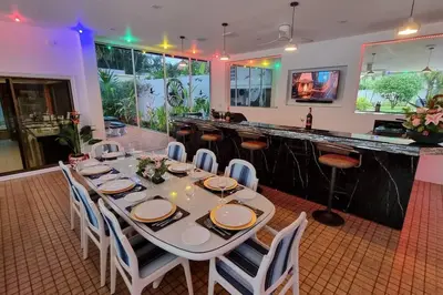 a dining room with a table and a bar at Baan Paa Phuket - 6 Bedrooms Villa in Rawai Beach