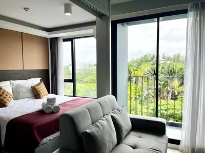 a bedroom with a bed and a couch and a large window at Aristo Resort Surin Beach M47 in Phuket Town