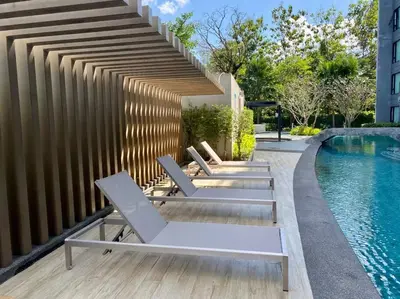 a group of lounge chairs sitting next to a swimming pool at Aristo Resort Surin Beach M47 in Phuket Town