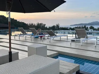 a row of chairs sitting on a deck with an umbrella at Aristo Resort Surin Beach M47 in Phuket Town