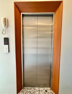 a glass elevator door in a room with a phone at The Brown Boutique Patong in Patong Beach