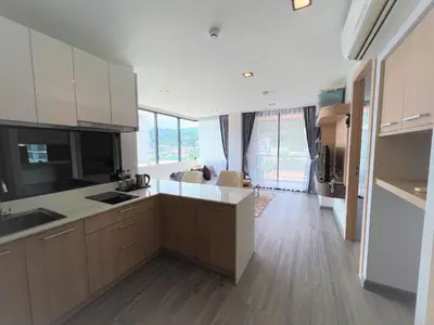 a kitchen with white cabinets and a large window at 1 bed Corner apartment in Kata - Grand Kata VIP in Kata Beach