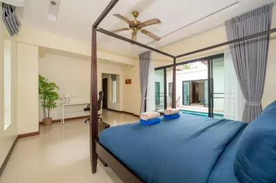 a bedroom with a blue bed and a large window at Rawai - 3 BR Private Pool Villa - Phoomjai Villa in Rawai Beach