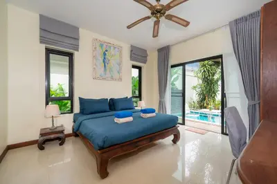 a bedroom with a blue bed and a balcony at Rawai - 3 BR Private Pool Villa - Phoomjai Villa in Rawai Beach