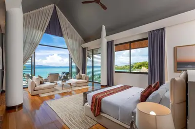 a bedroom with a bed and a view of the ocean at Villa Arun in Phuket Town