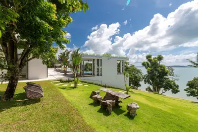 a house with a picnic table and chairs in the grass at Villa Arun in Phuket Town