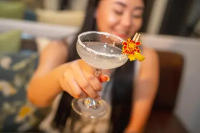 a woman holding a drink with a flower on it at Patong Social Hotel & Restaurant in Patong Beach