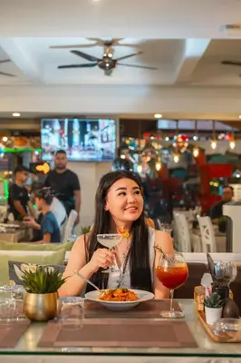 a woman sitting at a table with a plate of food at Patong Social Hotel & Restaurant in Patong Beach
