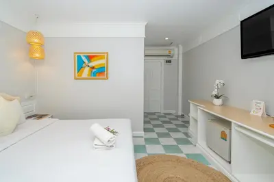 a white living room with a tv and a couch at Patong Social Hotel & Restaurant in Patong Beach