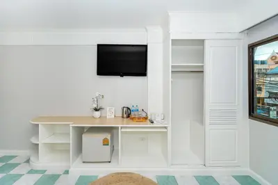 a white room with a table and a tv on a wall at Patong Social Hotel & Restaurant in Patong Beach