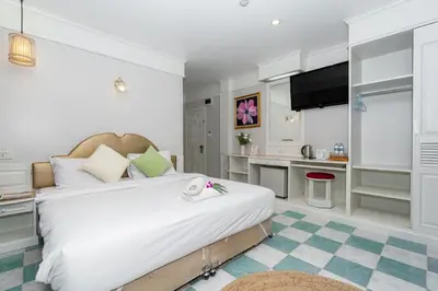 a bedroom with a large white bed and a kitchen at Patong Social Hotel & Restaurant in Patong Beach