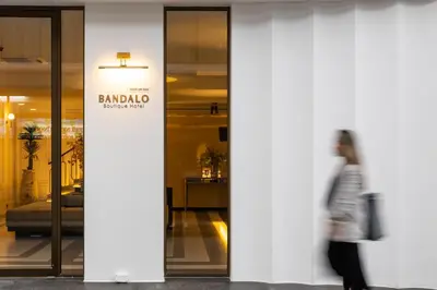a woman walks past a building with a sign on it at Bandalo Boutique Hotel - Patong Beach Road in Patong Beach