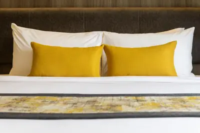 two pillows on a bed with two yellow pillows at Bandalo Boutique Hotel - Patong Beach Road in Patong Beach