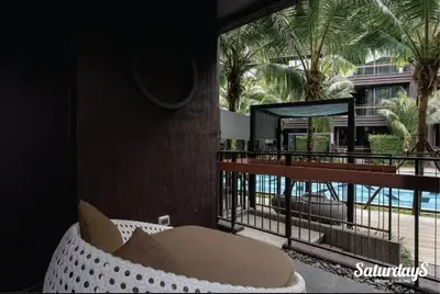 a room with a couch on a balcony with palm trees at Saturays condo One Bedroom Suite 178 in Ban Saiyuan (1)
