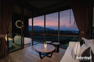 a living room with a couch and a large window at Saturays condo One Bedroom Suite 178 in Ban Saiyuan (1)
