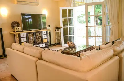 a living room with a couch and a tv at Shimmer Three-Bedroom Villa with large garden and two swimming pools in Rawai Beach